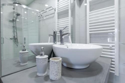 a white bathroom with a sink and a tub at Island Rodos Pool Suites in Ialysos