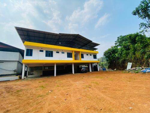 Casa blanca y amarilla con techo negro en Erumely Central Homes en Mundakāyam
