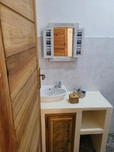 a bathroom with a sink and a wooden door at The Crafty Rooms in Gili Islands