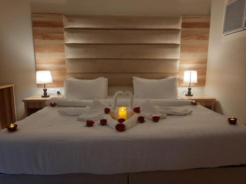 Una cama con una vela y rosas. en فندق دريم أملج, en Umm Lajj