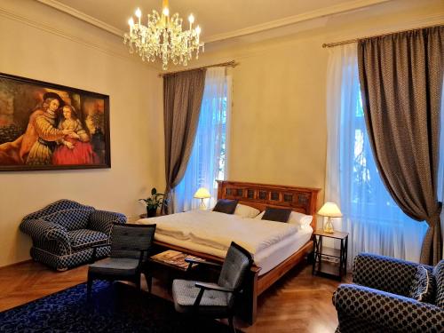 sypialnia z łóżkiem, 2 krzesłami i żyrandolem w obiekcie Palais Kneissl w mieście Burgau