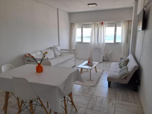een witte woonkamer met een tafel en een bank bij Enjoy Departamento Frente al Mar in Puerto Madryn