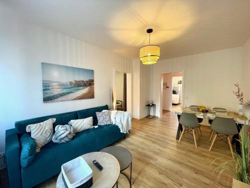ein Wohnzimmer mit einem blauen Sofa und einem Tisch in der Unterkunft Downtown Apartment by NINJA SPACES - Kingsize-Bett, Küche, Netflix, Terrasse in Wuppertal