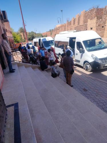 a group of people standing on a sidewalk next to vehicles at Hotel Rayyan l 'Escale in Ouarzazate