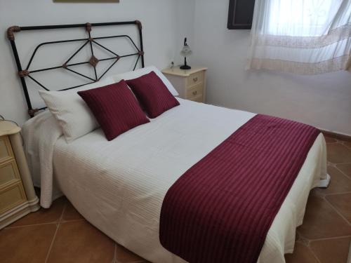 a bedroom with a large bed with two red pillows at Benavilla in Albuñol