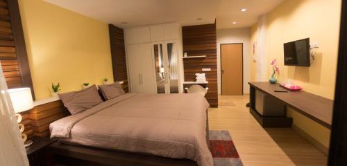 a bedroom with a large bed and a desk at Villa Rassada Nakorn Lampang in Lampang