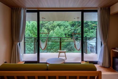 a living room with a green couch in front of a large window at Sakunami Onsen Yuzukushi Salon Ichinobo in Sendai