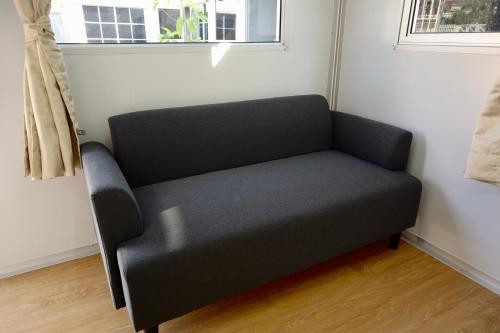 a black couch in a room with a window at Homey Hut Ayutthaya in Phra Nakhon Si Ayutthaya