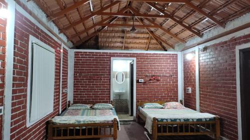 a room with two beds in a brick wall at Malpe Gruham Homestay Udupi in Malpe