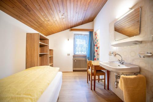 - une chambre avec un lit, un lavabo et une table dans l'établissement Apartments Karl, à Ortisei