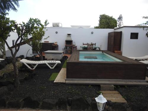 un patio trasero con piscina y una casa en Habitaciones Doña Cris, en Puerto del Carmen