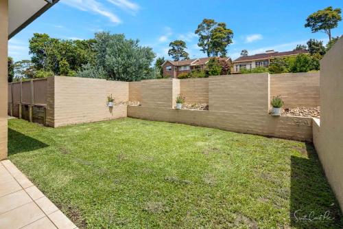 a backyard with a wooden fence and grass at Parker by the Sea in Batemans Bay