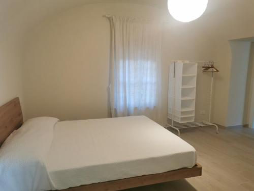 um quarto com uma cama branca e uma janela em Casa Rocca em Roccaforte Mondovì