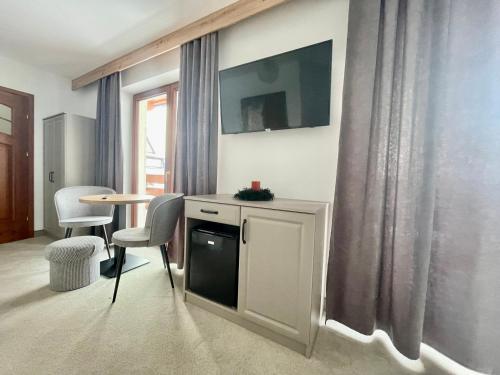 a living room with a tv and a table and chairs at Willa Joanna in Białka Tatrzanska