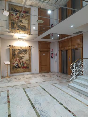 a lobby with a painting on the wall and stairs at Hotel Santa Cecilia in Ciudad Real