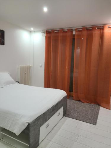 - une chambre avec un lit et des rideaux orange dans l'établissement Appartement meublé aux portes de Genève, à Annemasse