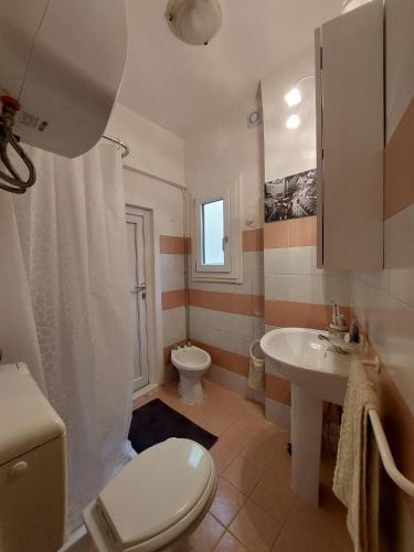 a white bathroom with a toilet and a sink at Casa Minniti in Syracuse