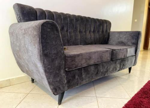 a grey couch sitting in a room with a red rug at The Matrix House in Kampala