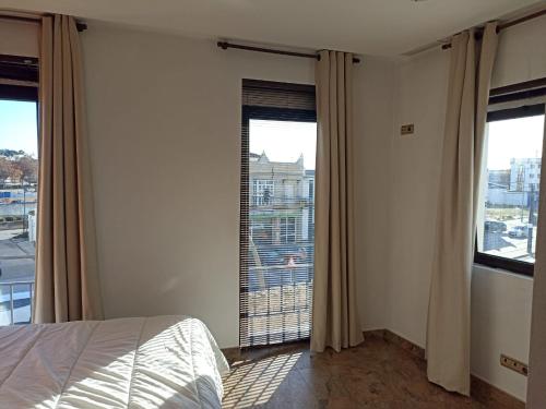 ein Schlafzimmer mit einem Bett und zwei großen Fenstern in der Unterkunft Avenida Reyes Católicos in Chiclana de la Frontera