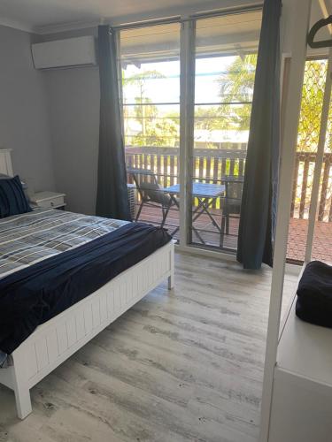 a bedroom with a bed and a balcony with a table at Kalbarri Reef Villa 3 in Kalbarri