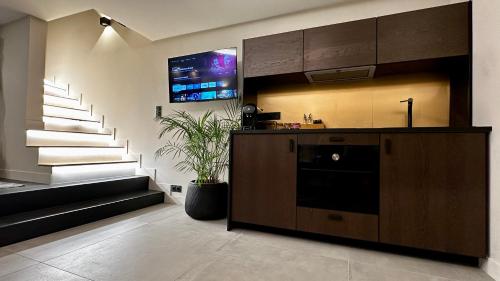 eine Küche mit einer Theke, einem TV und einer Treppe in der Unterkunft Maison Nina, Suite d’exception in Villeneuve-la-Garenne
