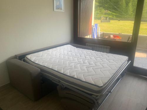 Bett in einem Zimmer neben einem Fenster in der Unterkunft Cervinia Ski In Ski Out - Studio with Terrace in Breuil-Cervinia