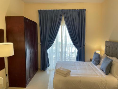 a bedroom with a bed with blue curtains and a window at Studio Apartment - Royal Breeze 05 in Ras al Khaimah