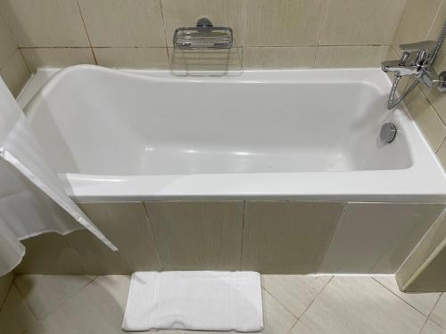 a white bath tub in a bathroom with a towel at Studio Apartment - Royal Breeze 05 in Ras al Khaimah