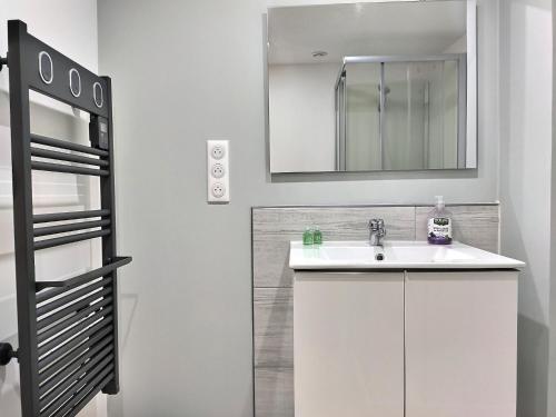 La salle de bains blanche est pourvue d'un lavabo et d'un miroir. dans l'établissement Le Tisseur de Rêves - Parking gratuit - Clim - Netflix, à Albi