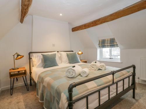 a bedroom with a bed with white walls and a window at Thomas Cottage in Wotton under Edge