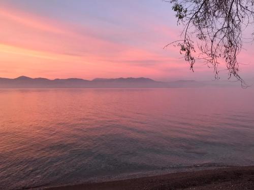 a sunset over the water with mountains in the background at Artemis Apartments in Diakopto