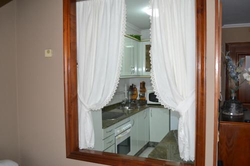 cocina con cortinas blancas y espejo en Coqueto Duplex en Vilagarcía de Arousa centro, en Vilagarcía de Arousa