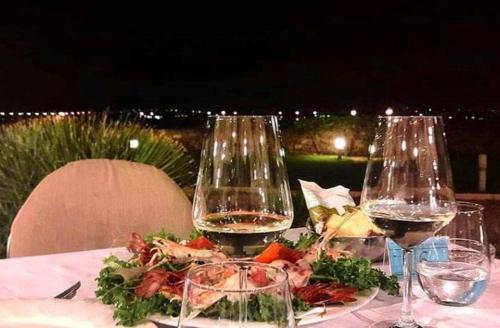 two glasses of wine and a plate of food on a table at Hotel Saraceno Al Faro in Taranto