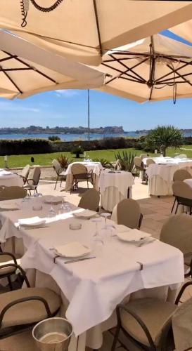 a table with white tables and chairs under an umbrella at Hotel Saraceno Al Faro in Taranto
