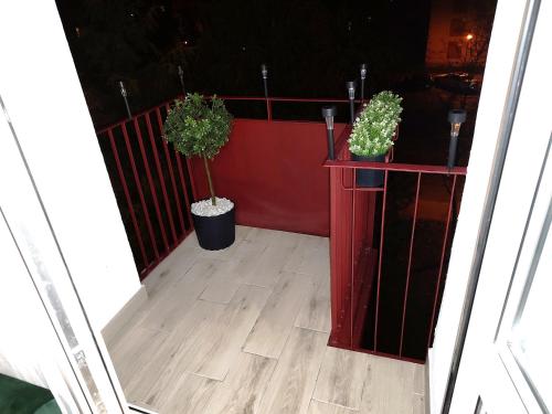 a balcony with two potted plants and a red fence at Złota Częstochowa in Częstochowa