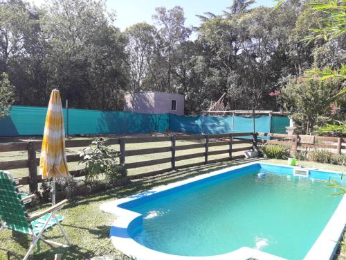 een zwembad met een parasol en een hek bij Sueño Bonito in San Andrés de Giles