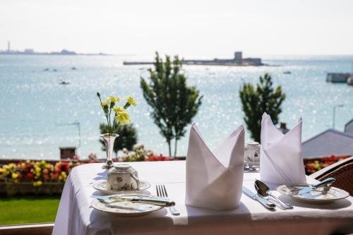 a table with a white table cloth with a view of the water at Panorama Guest House in Saint Aubin