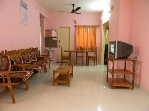 a living room with chairs and tables and a tv at Gerones Residency Serviced Apartments & Home Stays in Coimbatore