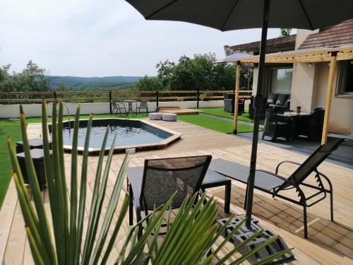 un patio avec un parasol et des chaises et une piscine dans l'établissement Suite climatisée jacuzzi privé, à Lachapelle-Auzac