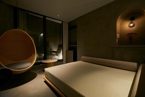 a bedroom with a bed and a chair and a window at Boutique Sauna ARCH in Tokyo