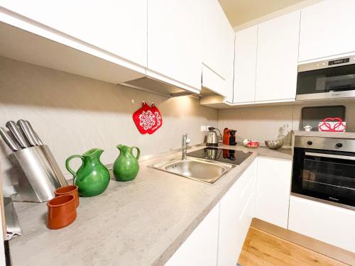 a kitchen with white cabinets and green vases on the counter at Suite Lagrange in Turin