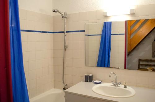 La salle de bains est pourvue d'un lavabo et d'une douche avec un miroir. dans l'établissement Granges 32 - Beau Duplex spacieux, au pied des pistes Domaine Alpe d'Huez, à Villard-Reculas