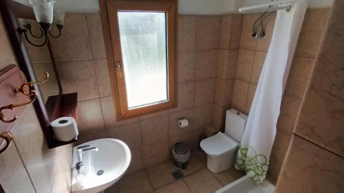 baño con lavabo y aseo y ventana en ResidenceTheo, en Selianitika