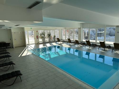a large swimming pool in a building with chairs at Panorama & SPA Apartment Kaiser Franz Josef I im Schillerhof in Bad Gastein