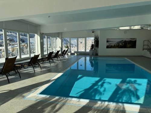 a large swimming pool in a building with chairs at Panorama & SPA Apartment Kaiser Franz Josef I im Schillerhof in Bad Gastein