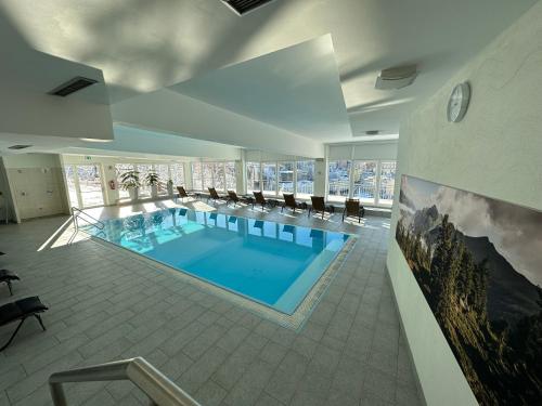 a large swimming pool in a building with chairs at Panorama & SPA Apartment Kaiser Franz Josef I im Schillerhof in Bad Gastein