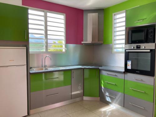 a kitchen with green and colorful walls at Gîtes Hotel Couleur Caraibes in Bouillante