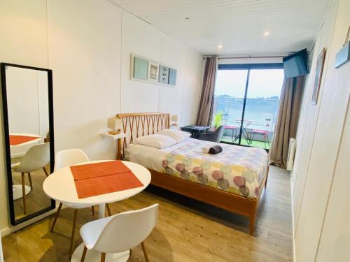 una camera da letto con un letto, un tavolo, un tavolo e delle sedie di Apt 204, Vue Mer, Accès plage Trestraou, Perros-Guirec a Perros-Guirec