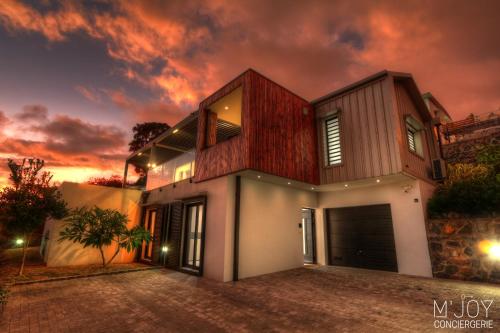 uma casa com um pôr-do-sol ao fundo em Villa Azur Saint-Gilles - La Réunion - Seaview, Pool, Beach & BBQ! em Saint-Gilles-les-Bains