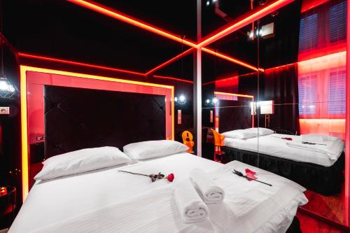 two beds in a room with red lights at Hotel Aura Design & Garden Pool in Prague